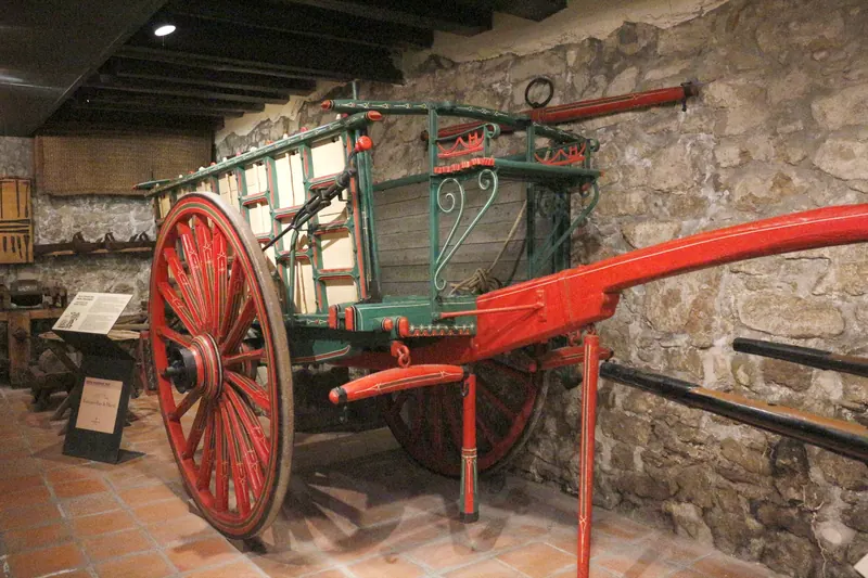 Carro verd i vermell davant d’una paret de pedra