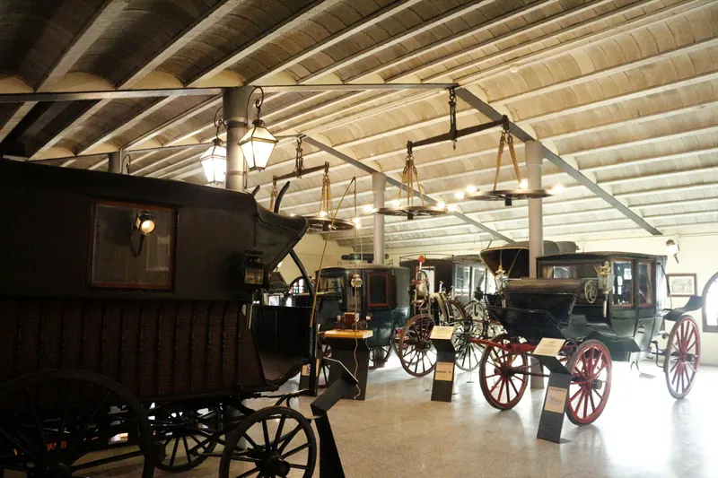 Sala dels carruatges amb carrosses antigues i rodes penjades del sostre