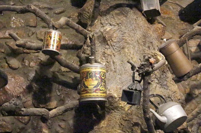 Estris de cuina antics penjats en una paret de pedra